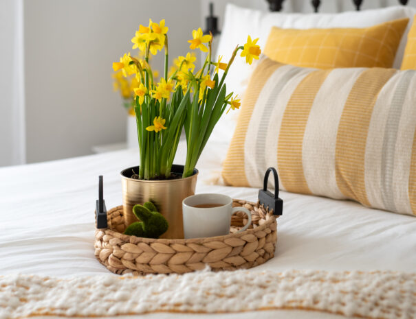 Yellow daffodils and a cup of tea on a tray in a light and bright bedroom
